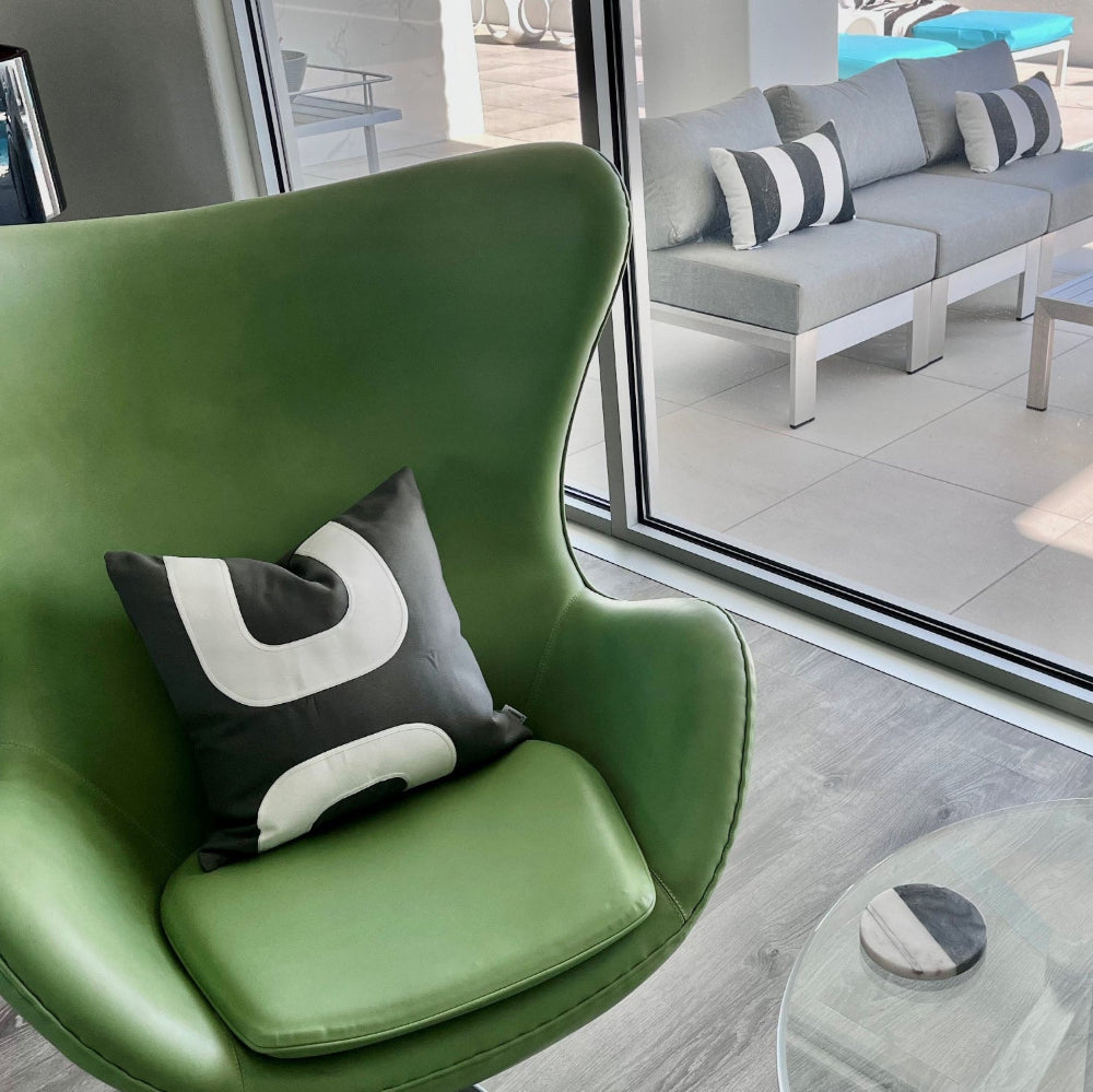 grey and white mid century modern pillow on a green leather egg chair