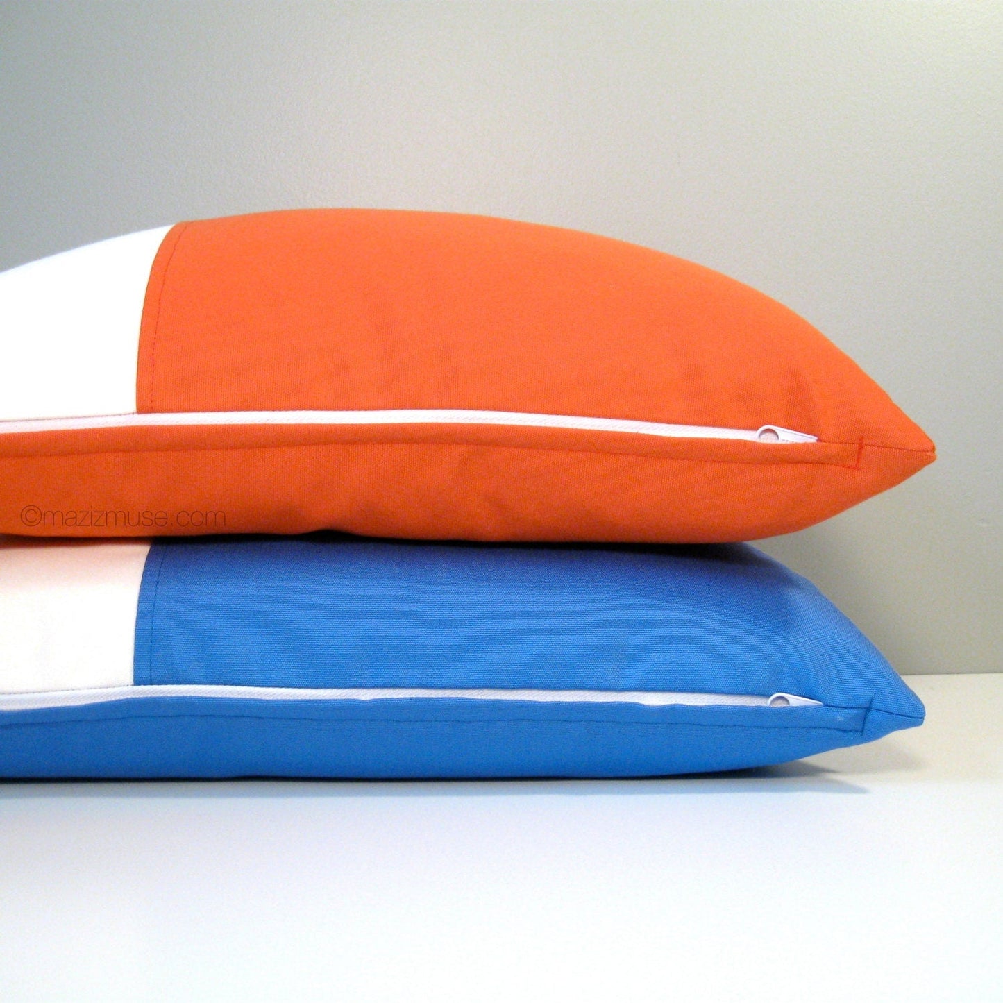 two sunbrella outdoor pillows in orange and white and capri and white showing zipper closure