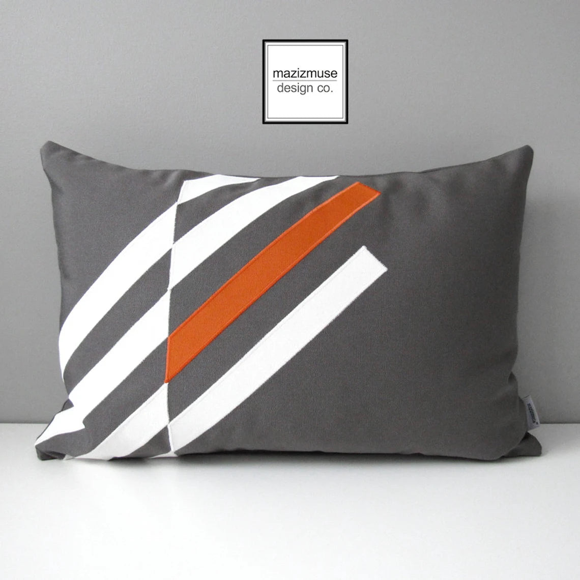 gey adn white sunbrella pillow with orange geometric accent for outdoor patio