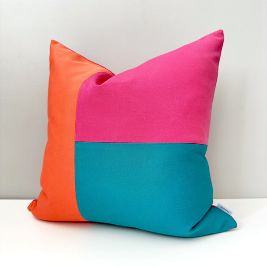 Colorful pillow with orange, pink, and teal color block deisgn
