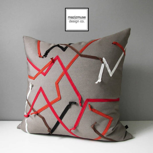 taupe sunbrella outdoor pillow with red orange black and white trim in an abstract design. one of a kind!