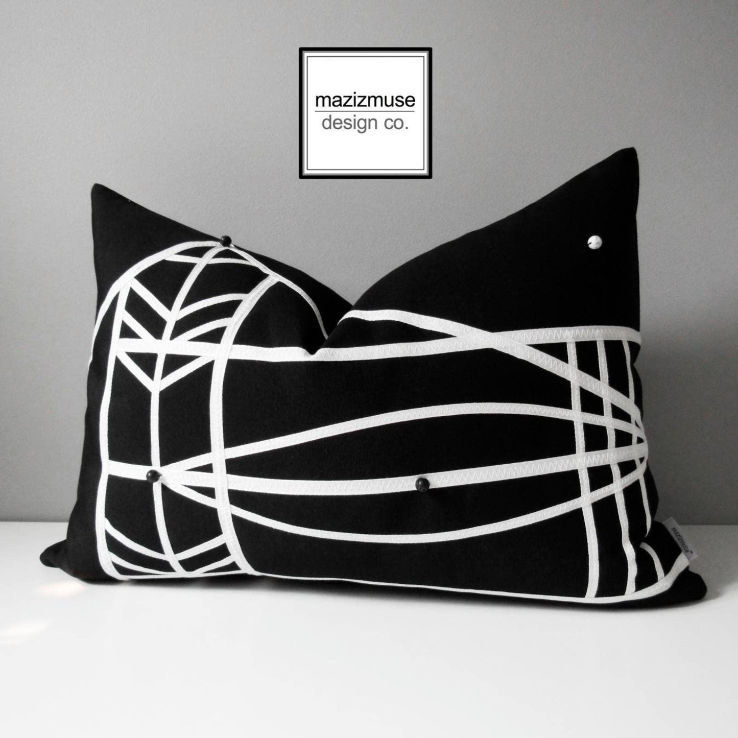 black and white sunbrella outdoor pillow in geometric micronesian design including lava bead and howlite detail.